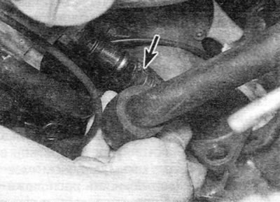 Figure 13.8. Disconnecting the coolant hose (marked with an arrow) from the rear of the cylinder…