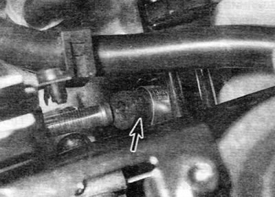 Figure 13.9. Disconnecting the coolant hose (marked with an arrow) from the front of the cylinder…